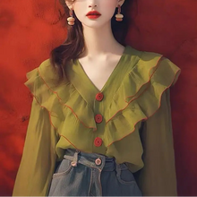 Load image into Gallery viewer, Woman wearing a green blouse with ruffled details against a red background