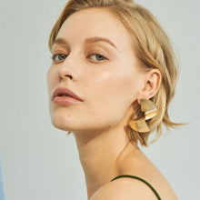 Load image into Gallery viewer, A person wearing twisted spiral earrings with a metallic finish.
