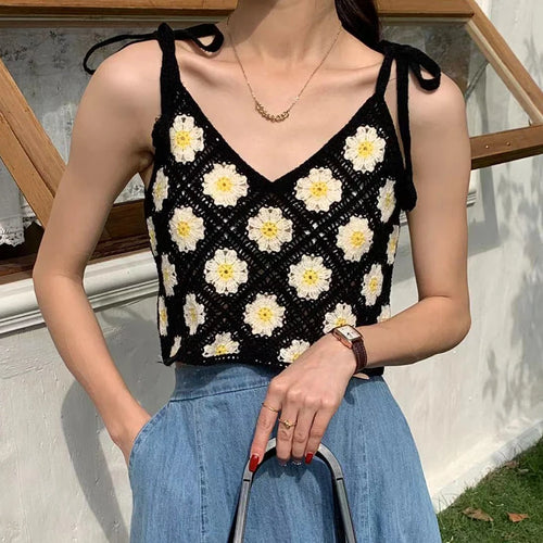Woman wearing a black floral crochet top and blue jeans outdoors.