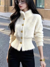 Load image into Gallery viewer, Woman wearing a white knitted cardigan with gold buttons on a street.
