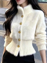 Load image into Gallery viewer, White knitted cardigan with gold buttons worn by a person outdoors.
