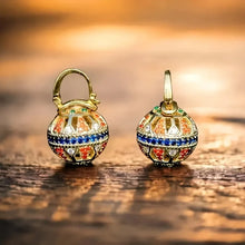 Load image into Gallery viewer, Pair of gold earrings with colorful gemstones on a wooden surface
